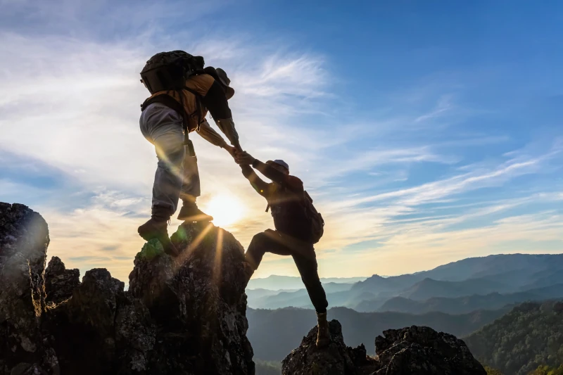 hikers climbing and helping each other